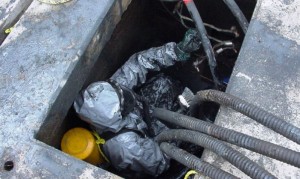 Spill responder performs confined space entry to decontaminate cement utility vault. 