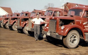 Harold standing with his truck line-up. (1960)